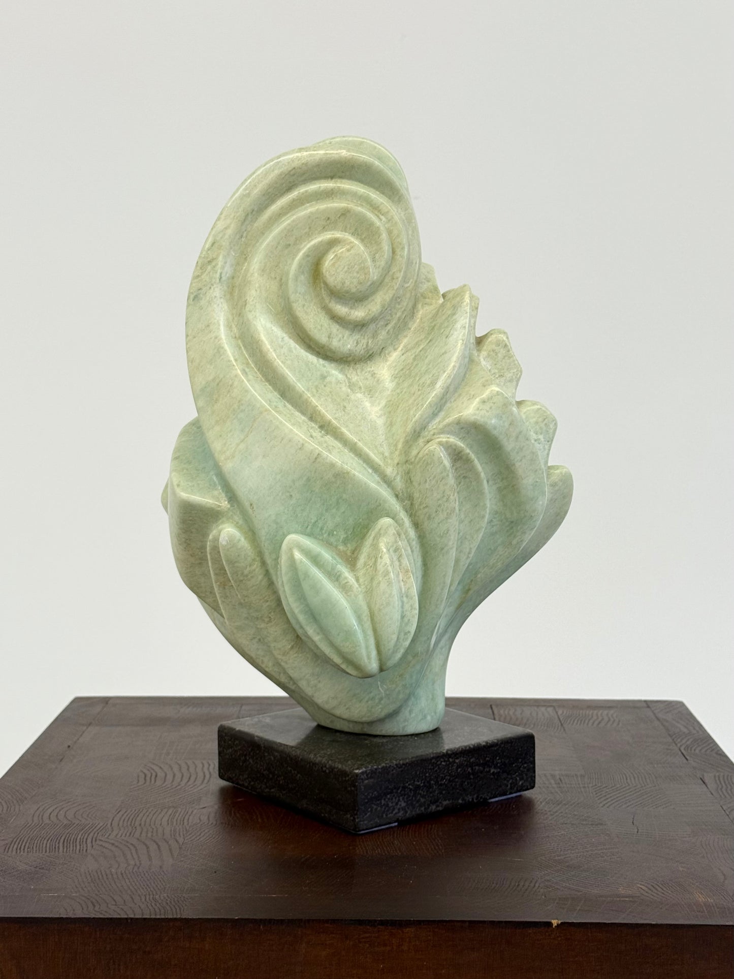 Groene natuursteen sculpture op marmeren Sokkel