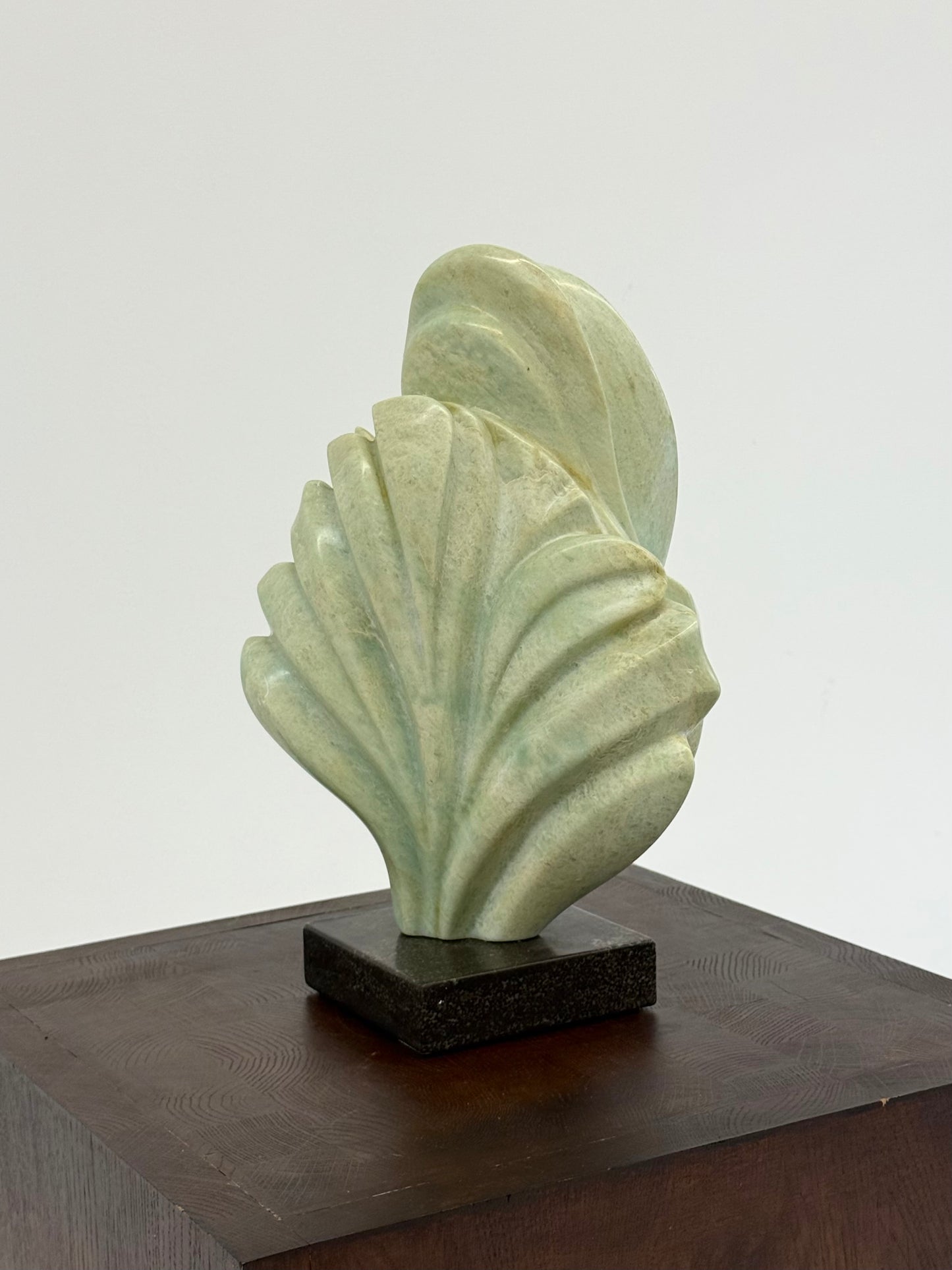 Groene natuursteen sculpture op marmeren Sokkel